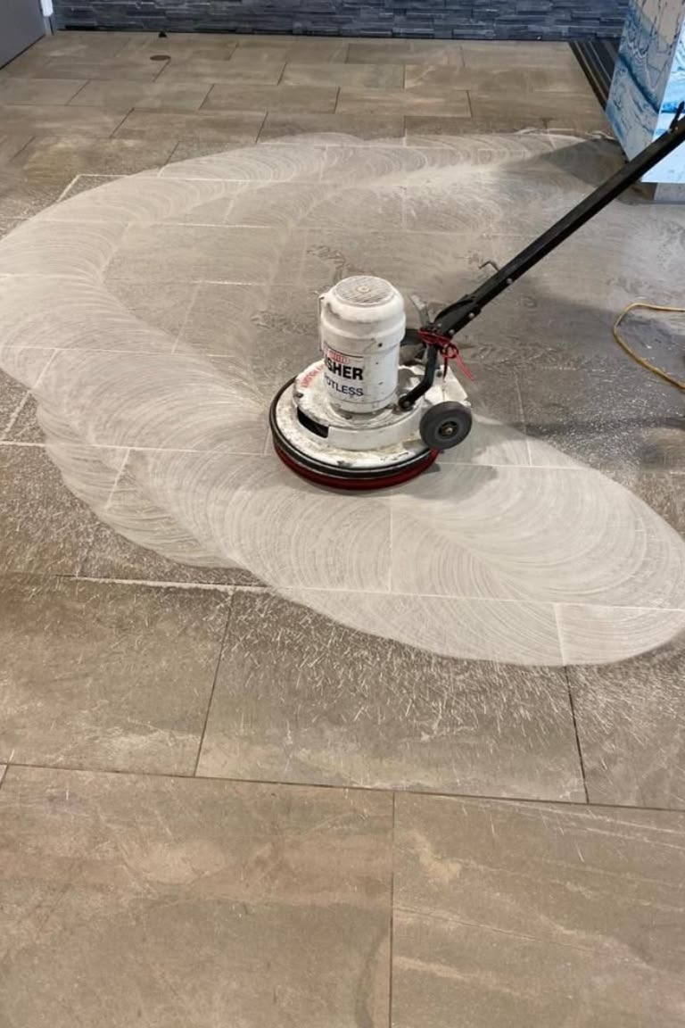 Professional floor buffer polishing a large stone tile floor mid-clean
